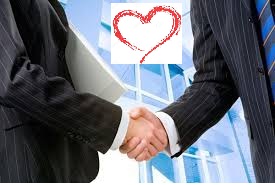 Imagen de dos hombres de negocios estrechando las manos y de fondo edificios corporativos con una silueta de un corazón en la fachada